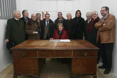 2. Elena Oró, asseguda a la taula del seu pare envoltada dels representants de la Fundació..