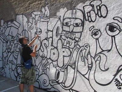 Foto 3. L'artista s'encarrega de pintar un grafit a la paret mitgera de l'aparcament.