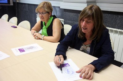 Puri Terrado, en presència de Montse Parra, mostra el cartell de la temporada, amb una "orella" en clau de Fa..