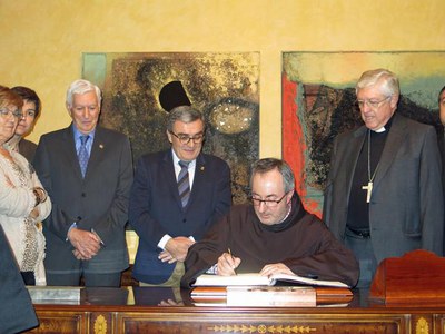 El pregoner, el pare franciscà Joaquim Recasens, signant en el Llibre d'Honor de la Paeria.