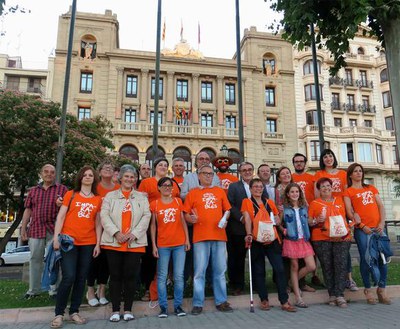 L'alcalde Ros i els regidors Rodamilans i Simó amb el grup de voluntaris que han assistit a l'encesa de llums de color taronja.
