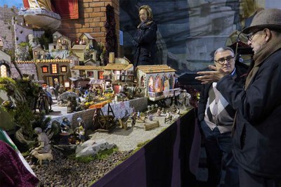 L'alcalde i Mn. Agelet conversen davant el pessebre.