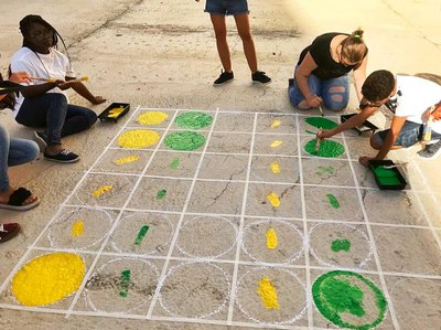Joves dels centres oberts del Centre Històric pinten jocs tradicionals en una plaça del barri. L’objectiu és revitalitzar aquest espai per fomentar u….