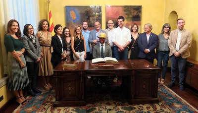 Abans del pregó, el Sr. Postu ha signat en el llibre d'honor de la Paeria, envoltat de l'alcalde i els regidors.