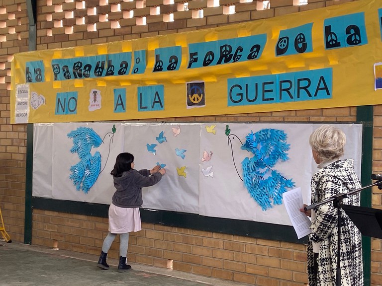 Els infants han enganxat figures al·legòriques a la pau en la pancarta que han desplegat contra la guerra
