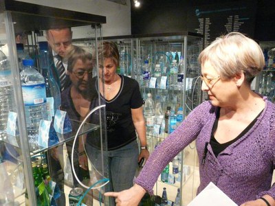 La regidora de Cultura, Montse Parra, atèn les explicacion sobre la col·lecció d'ampolles que forma part de l'exposició..