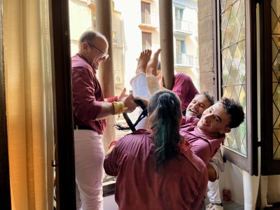 El regidor de Festes, Xavi Blanco, ajuda a entrar per un dels finestrals de la Paeria als Castellers dels pilars de comiat.