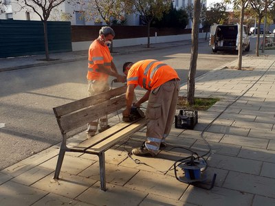 Dos operaris treballen en el manteniment d'un banc.