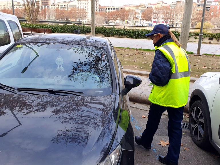 Una treballadora de l'EMAU revisa un vehicle aparcat