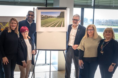 L'alcalde amb els regidors i els representants veïnals al costat de la imatge de la proposta del tram central de la canalització.