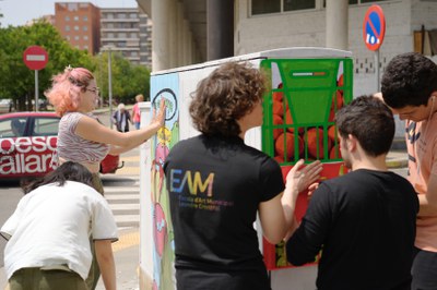 Alumnes de l'Escola Municipal d'Art treballant en la decoració d'un armari de connexions a l'avinguda Joana Raspall.