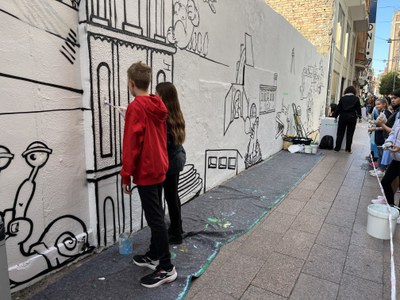Un noi i una noia pintant el mural, aquest dimarts.