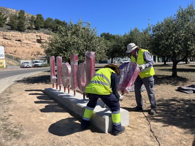 Els operaris instal·lants les lletres a l'entrada de la ciutat.