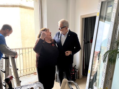 L'alcalde saluda la Trini, inquilina d'aquest habitatge de l'EMAU on ara es fan obres de millora de l'eficiència energètica.