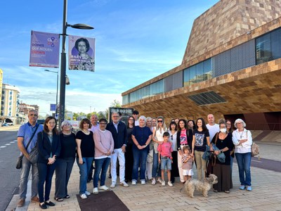 L'alcalde, Fèlix Larrosa, la tinenta d'alcalde Carme Valls, la regidora Pilar Bosch i la comissionada de Polítiques Feministes, Verònica Martínez, amb familiars, persones vinculades a algunes de les protagonistes i dones del Consell Municipal de les Dones de Lleida, sota una de les banderoles.