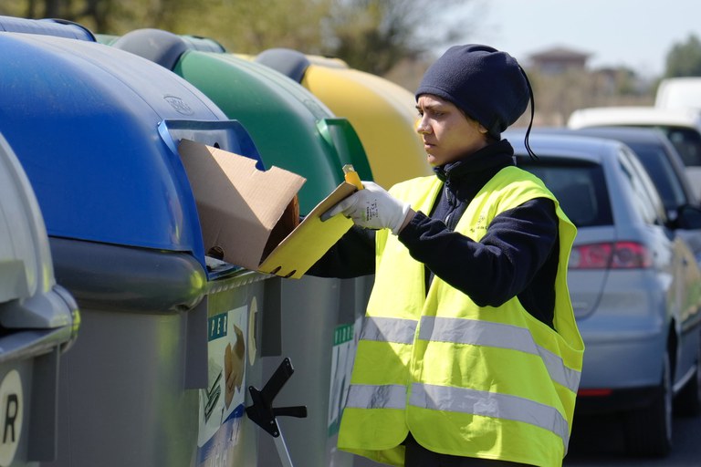 Una de les treballadores del servei diposita una capsa de cartró al contenidor blau