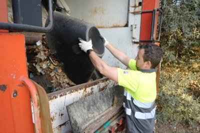 Un operari diposita les deixalles i restes vegetals en el camió.