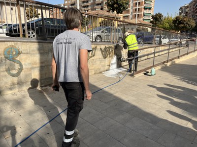 Tasques de neteja de pintades a la plaça dels Pagesos.