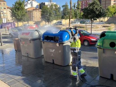 Neteja d'una illa de contenidors amb aigua a pressió.