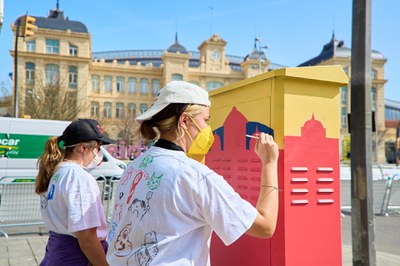 Dos de las alumnas trabajando en la decoración de uno de estos elementos de mobiliario urbano, frente a la estación.
