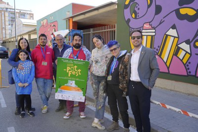 La organización del PotFest y las autoridades municipales con la artista Amaia Arrazola frente a su mural en la fachada del Colegio Frederic Godàs.