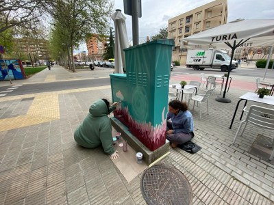 Alumnos de la Escuela de Arte Municipal Leandre Cristòfol trabajando en la intervención artística con grafito que se está llevando a cabo en 7 armarios de instalaciones de Lleida.