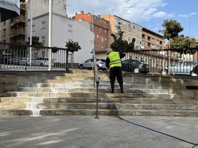 Un operario trabajando en la limpieza con agua a presión en la plaza dels Pagesos, esta mañana.